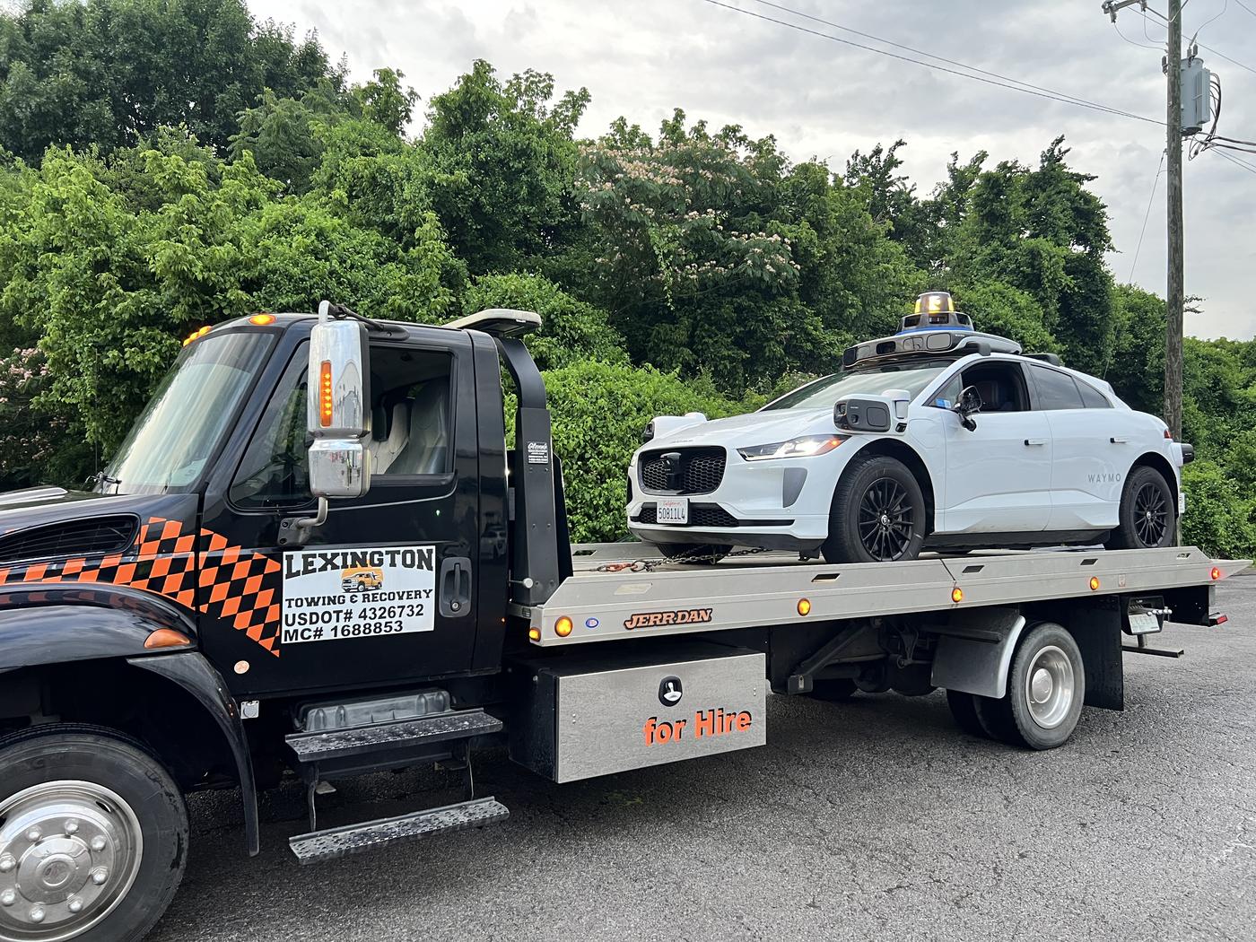 Lexington Towing & Recovery flatbed truck transporting a self-driving vehicle